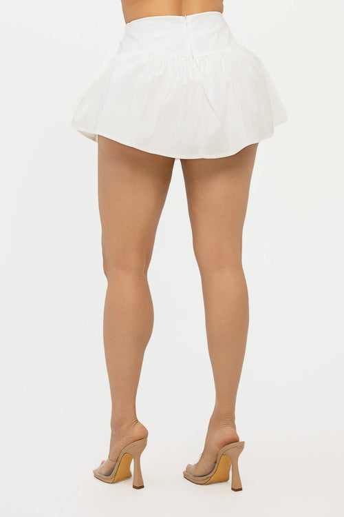 Back view of a woman wearing a white Poplin mini skort women with stylish design and chic silhouette.